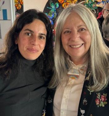 two women smiling, one with long gray hair, one with black hair