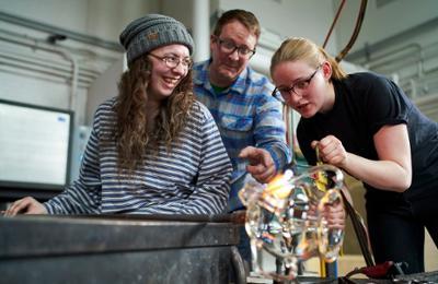 three students in glass art hot shop
